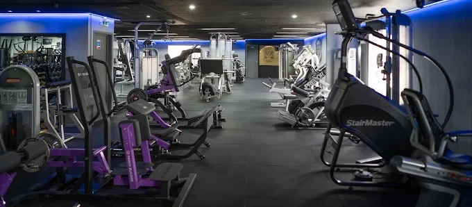 The main training floor at Bodyworks Gym Featherstone looking down the room, with resistance machines, StairMasters and blue LED lighting