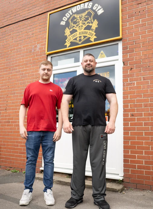 Owners Mark and Jason standing outside Bodyworks Gym Featherstone beneath the gym sign