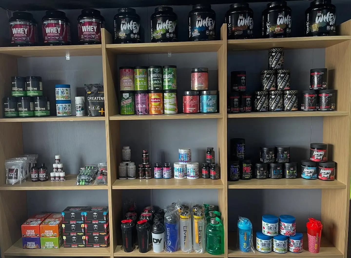 Shelves stocked with whey protein, creatine, pre-workout, greens and shakers at the Bodyworks Gym Featherstone supplement counter